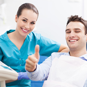 Smiling man in dental chair giving thumbs up